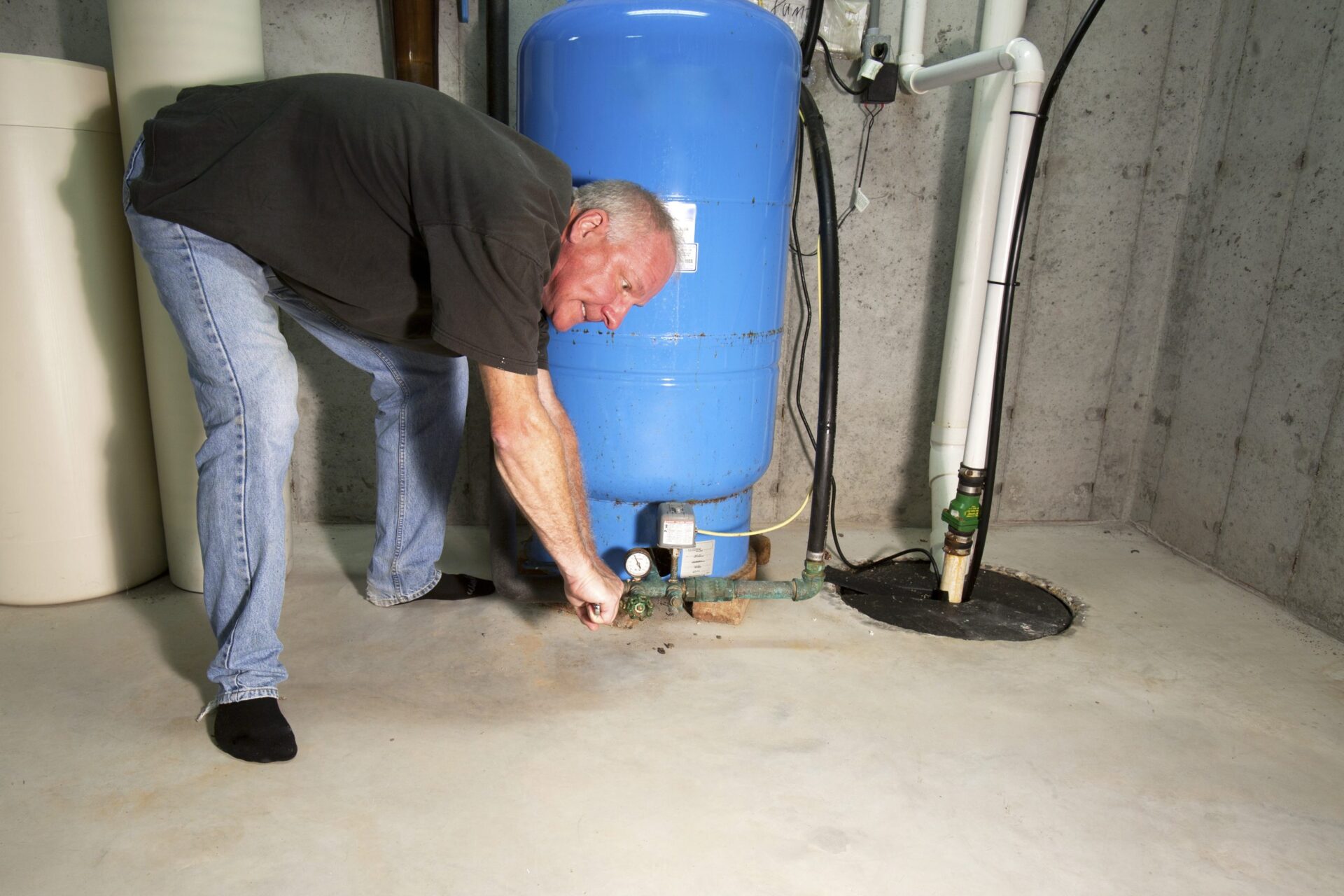 Man with angry, red face bent over sump pump with a wrench